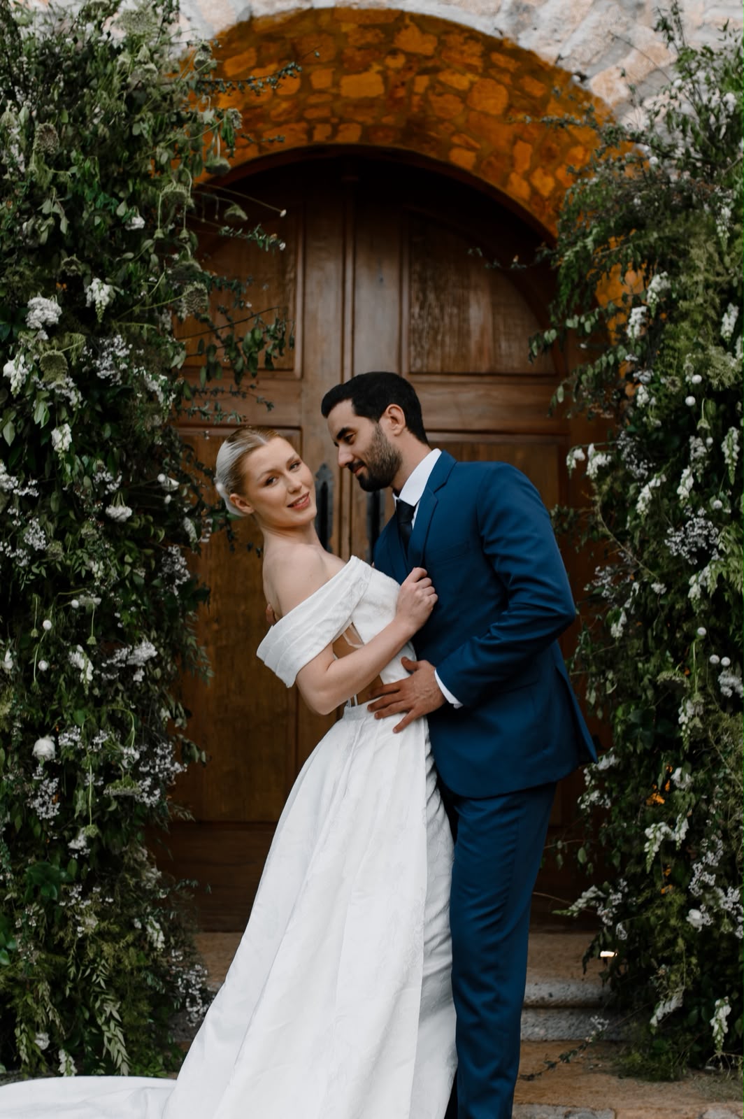 Retrato dos noivos junto a um arco de jardim